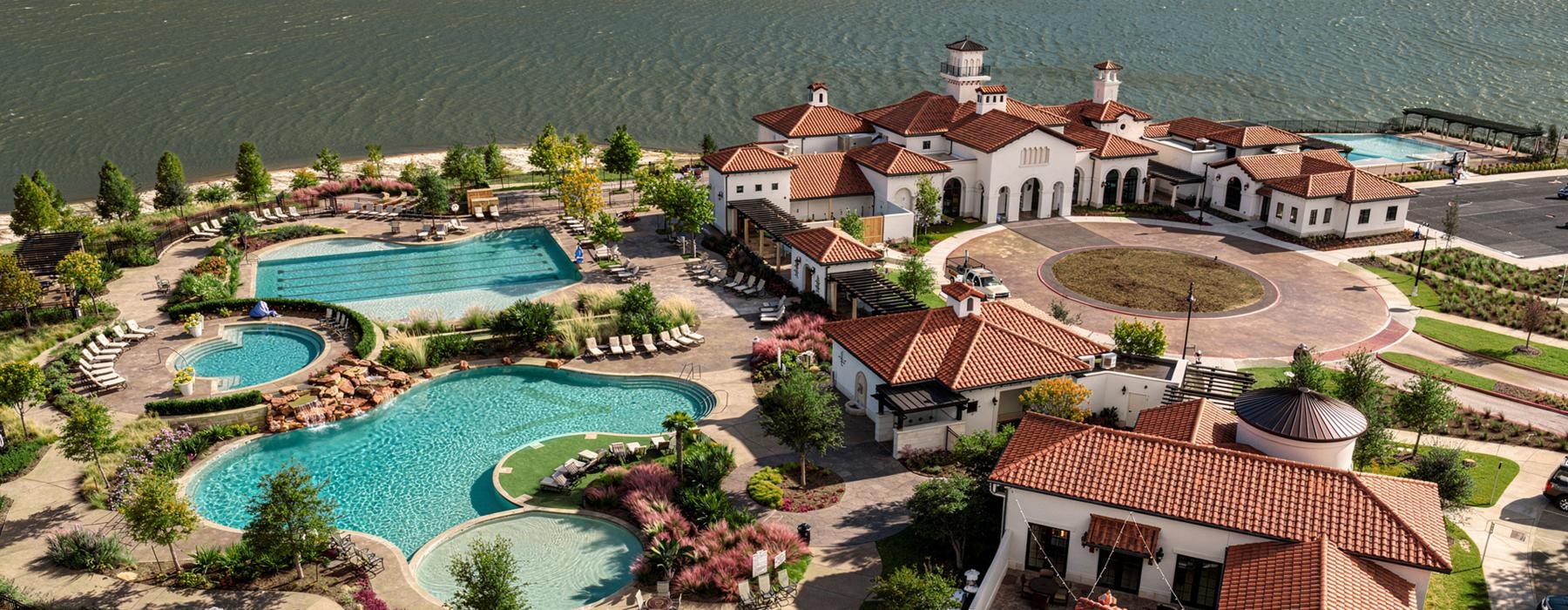 a high angle view of a resort with pools and body of water